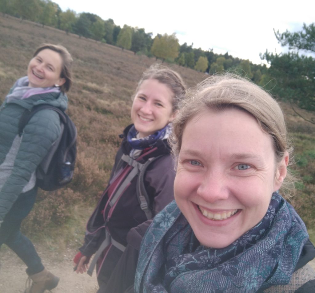 Drei Frauen wandern durch flache Heidelandschaft